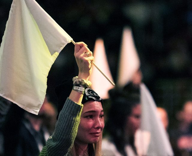 A woman and other in the background holding up a white flag in the Urbana 18 conference