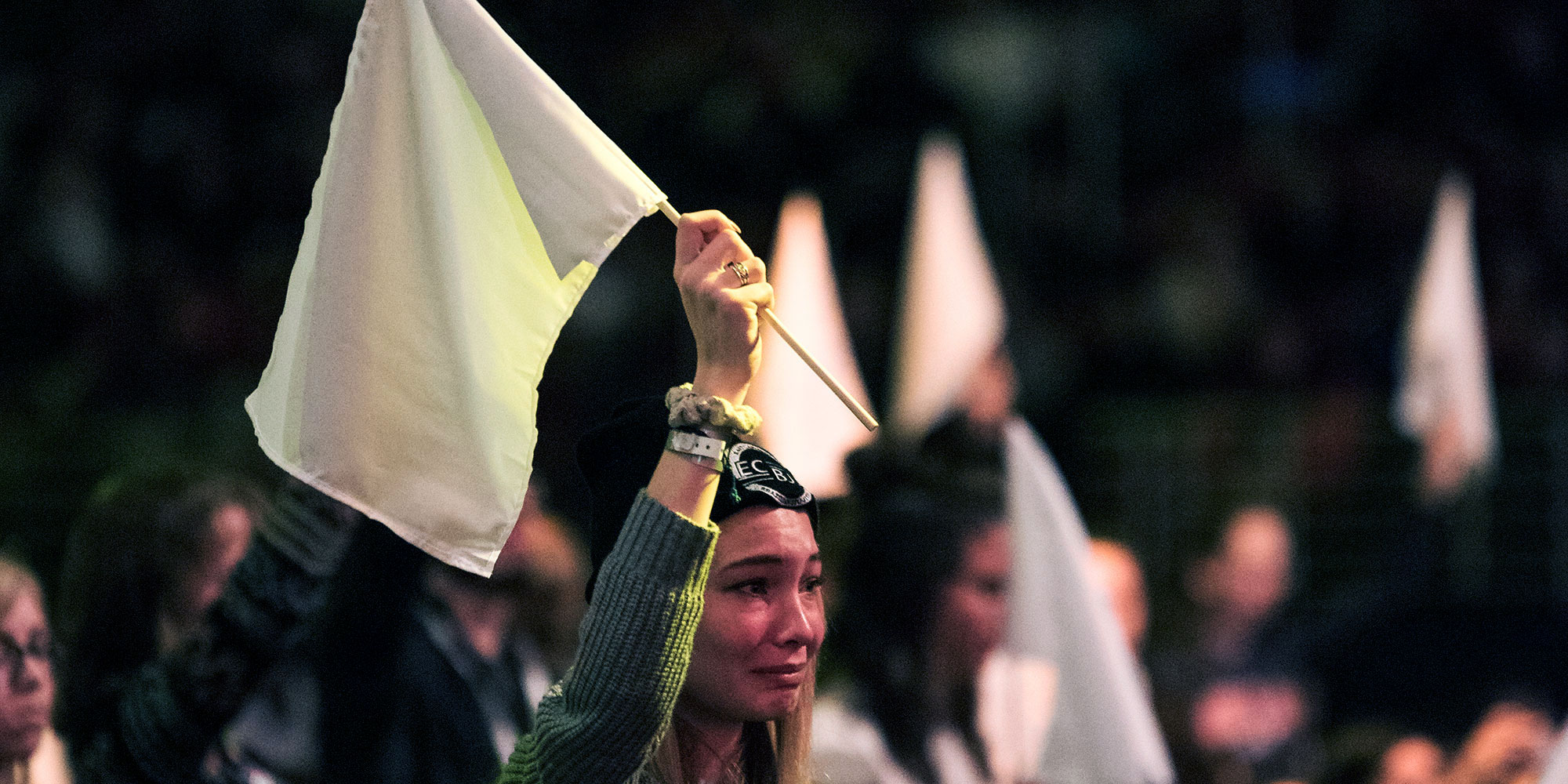A woman and other in the background holding up a white flag in the Urbana 18 conference