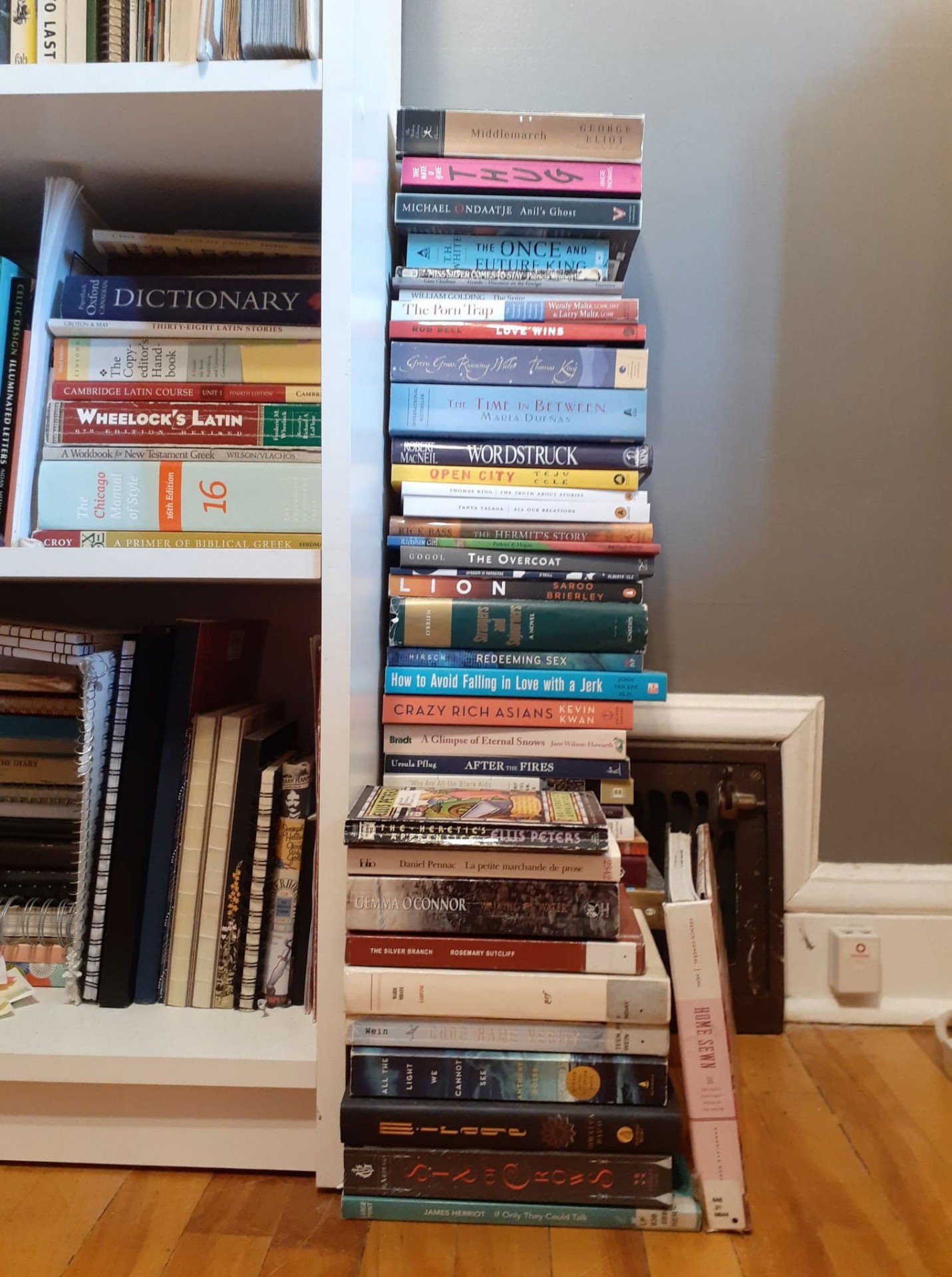 A photo of stack of books inside and beside a bookshelf