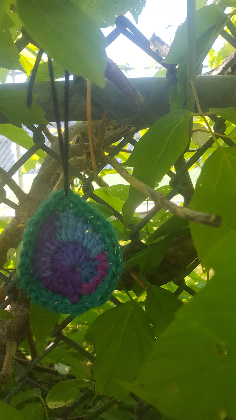 A photo of a knitted decoration hung on a tree branch
