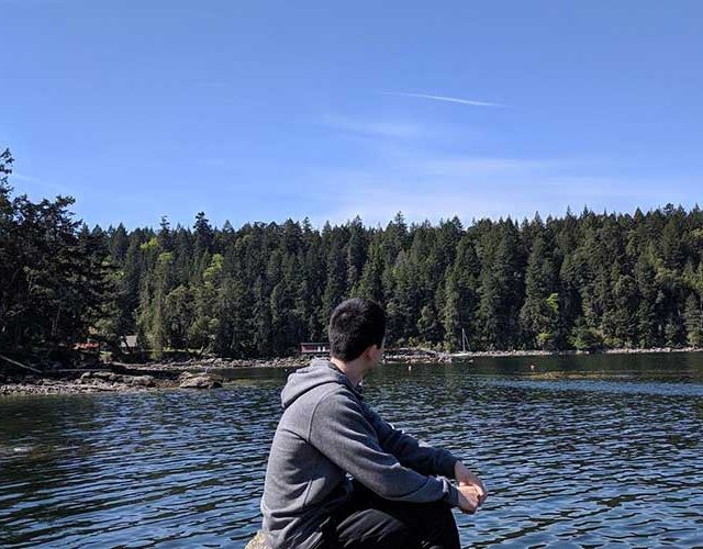 Photo of the student author of this article sitting in front of a lake