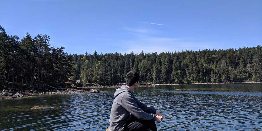 Photo of the student author of this article sitting in front of a lake